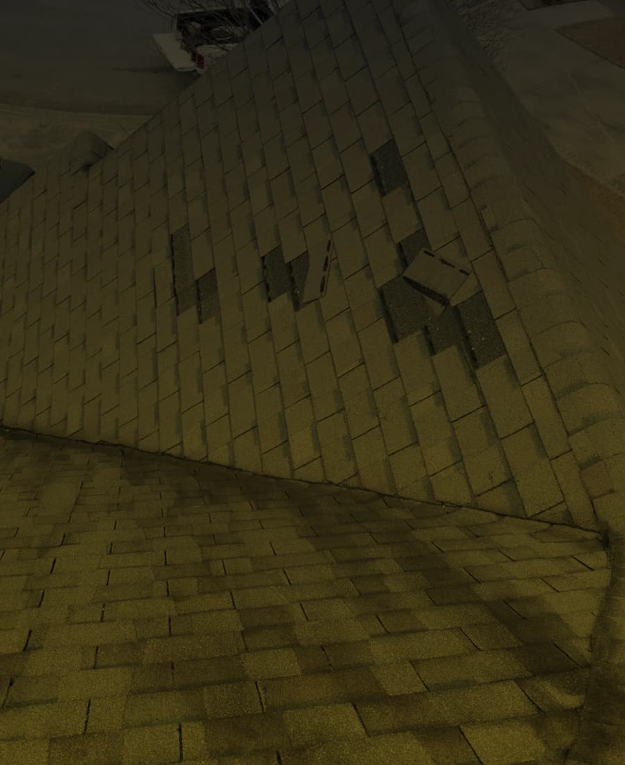 Damaged asphalt shingles at a roof transition