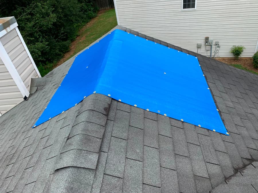 Blue temporary covering secured over a residential roof area