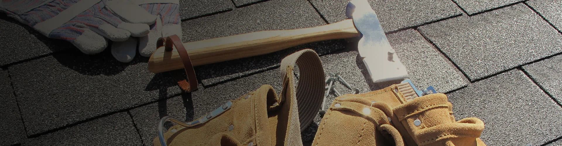 Roofing tools arranged on an asphalt shingle surface