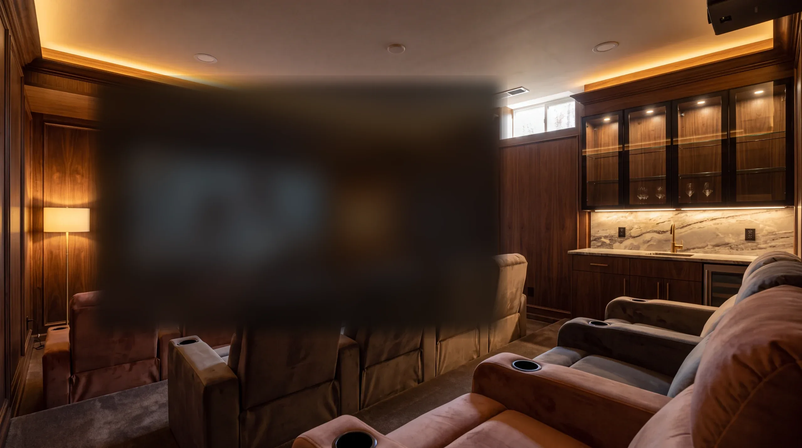 Basement media room with tiered seating, wood paneling, and a wet bar.