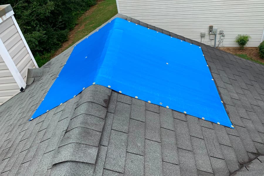 Blue temporary covering secured over a residential roof area
